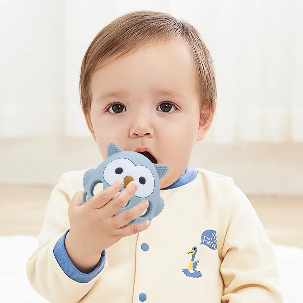 Baby holding blue hollow owl silicone teether, safe BPA-free chew toy with open grip design