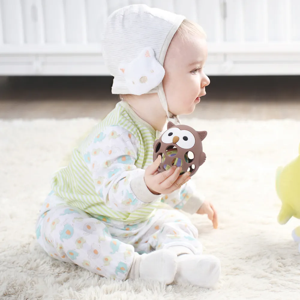 Baby playing with brown hollow owl silicone teether ball, lightweight food-grade chew toy for teething relief