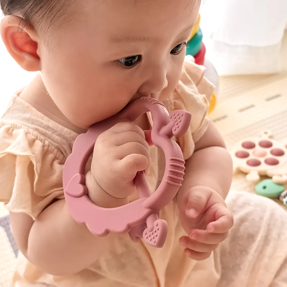 Baby chewing a dark pink Cupid Heart Handle Teether—lightweight heart frame with arrow handle provides soothing teething relief.