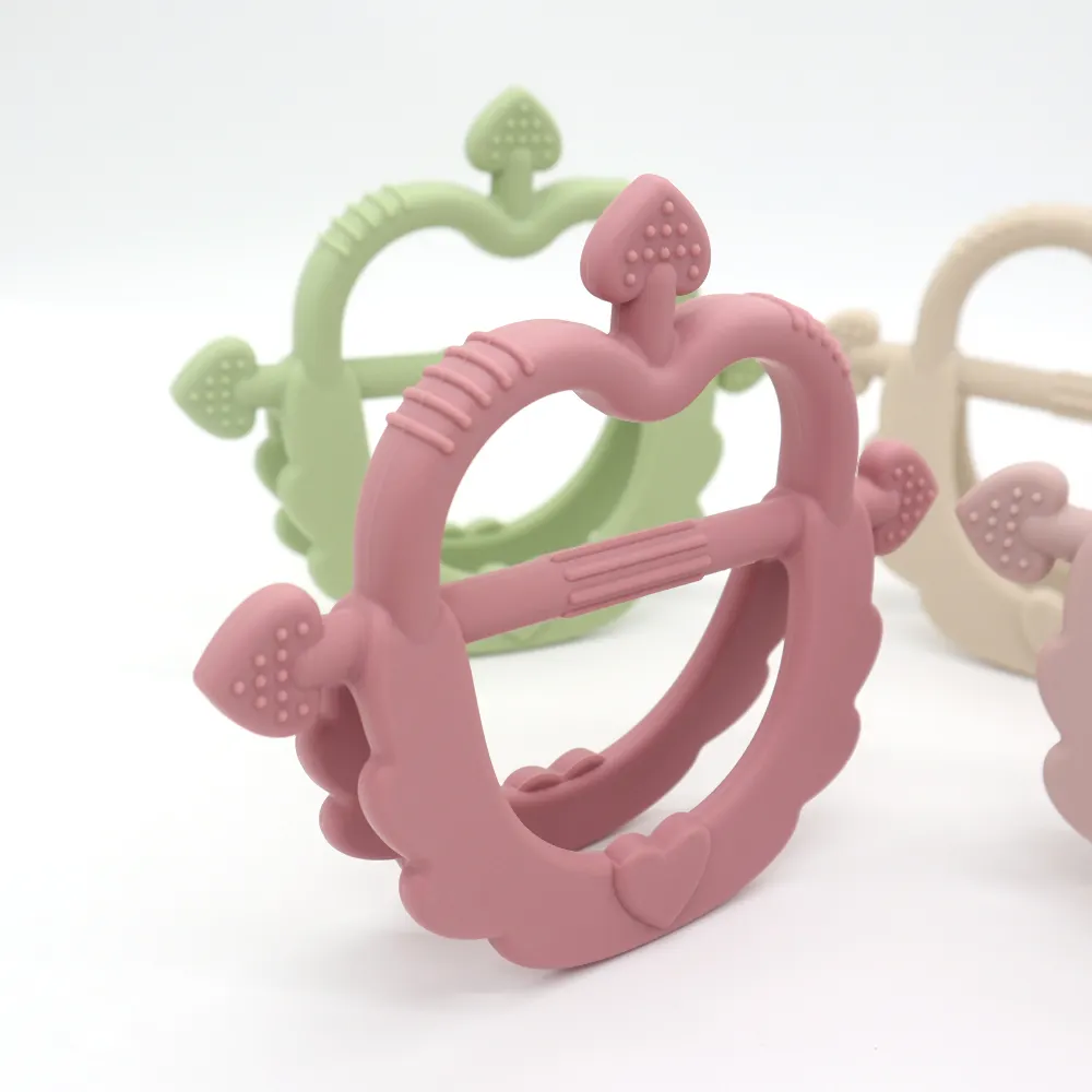 Dark pink Cupid Heart Handle Teether close-up showing textured arrow tips and ribbed bite zone, food-grade silicone for safe chewing.