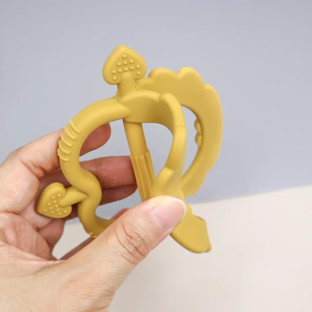 Hand bending the mango Cupid Heart Handle Teether to demonstrate flexible, durable silicone and ergonomic center bar for gripping.